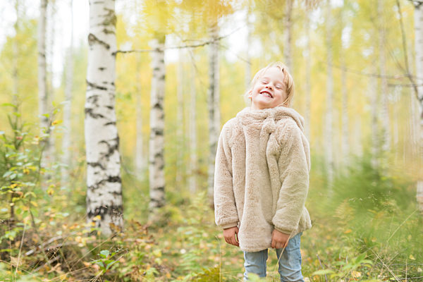 Portrait of laughing blond girl playing in autumnal forest