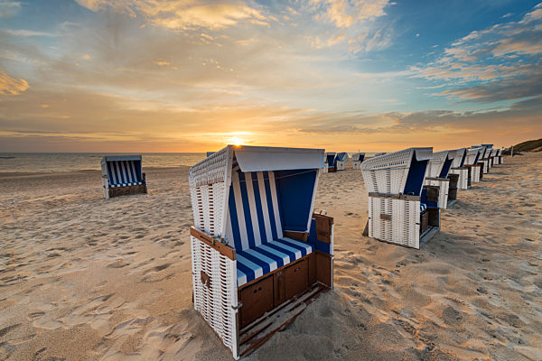 Germany, Sylt, North Sea, sandy beach with hooded beach chairs in sunset