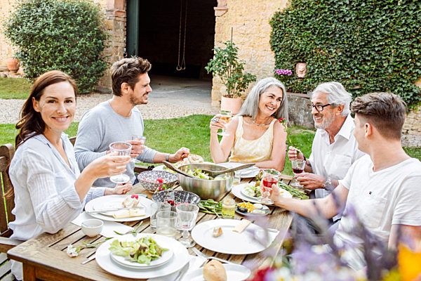 Happy family eating together in the garden, clinking glasses