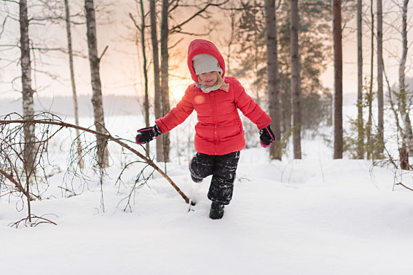 Finland, Kuopio, happy toddler girl running in winter landscape at sunset