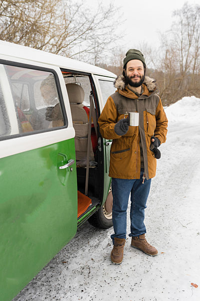 Portrait of smiling man with electric van in winter landscape, Kuopio, Finland