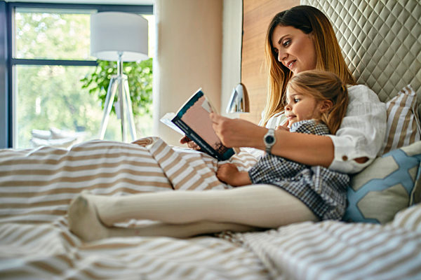 Mother and daughhter reading a book in bed