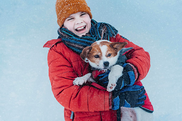 Portrait of laughing boy and his dog in winter