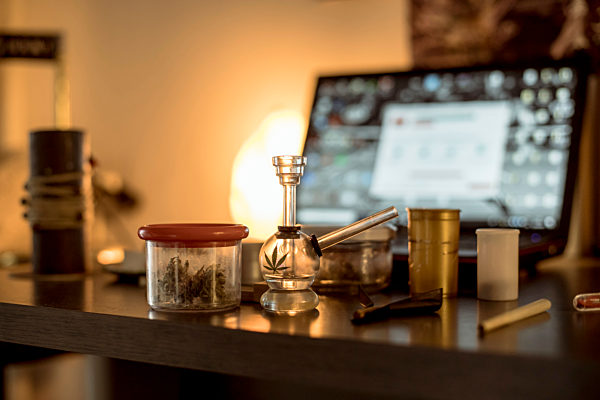 Marijuana in a jar, with hashpipe and joint on table