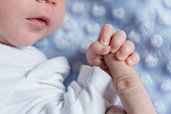 Newborn baby boy holding finger