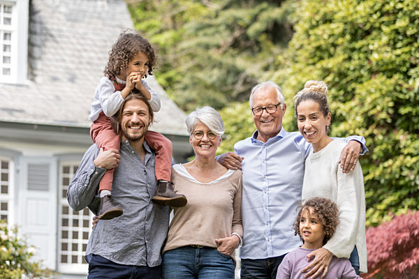 Happy extended family standing in garden of their home