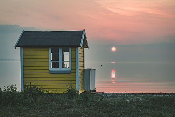 Denmark, Aeroe, Aeroskobing, Sunset scenery with traditional baths on beach 
