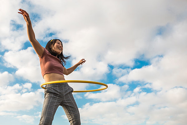 Happy woman playing with hula hoop outdoors