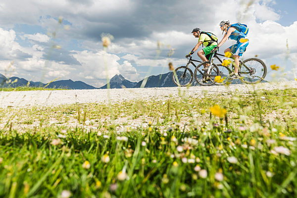 Couple mountainbiking on gravel path in the mountains, Achenkirch, Austria