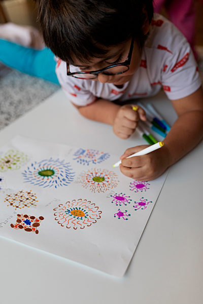 Little boy lying on the floor at home drawing flowers