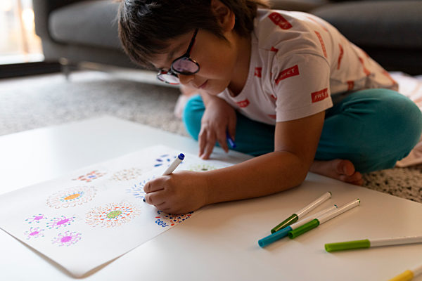 Boy sitting on the floor at home drawing flowers