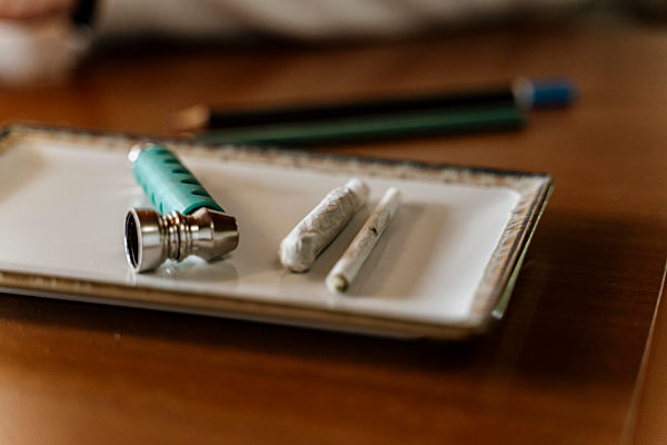 Close-up of marijuana joints and pipe in tray on table