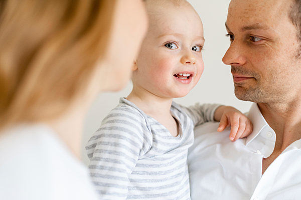 Parents looking while holding baby boy at home