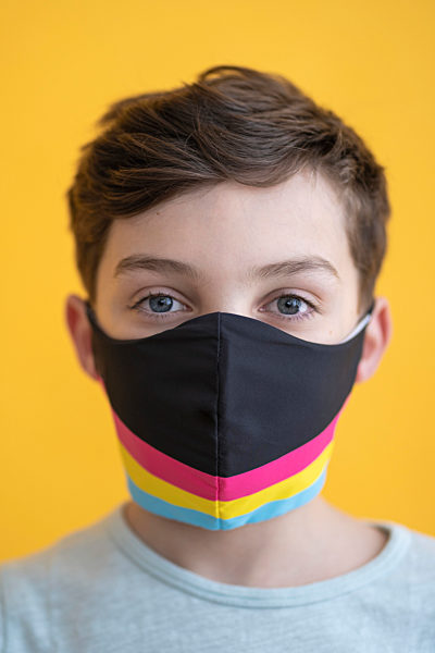 Close-up of boy wearing multi colored mask against yellow background