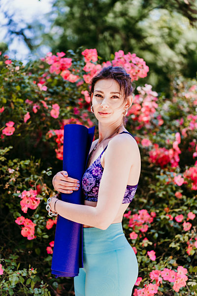 Beautiful woman holding yoga mat in park