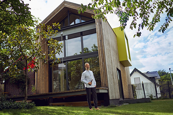 Mature man holding beer bottle while standing against modern tiny house