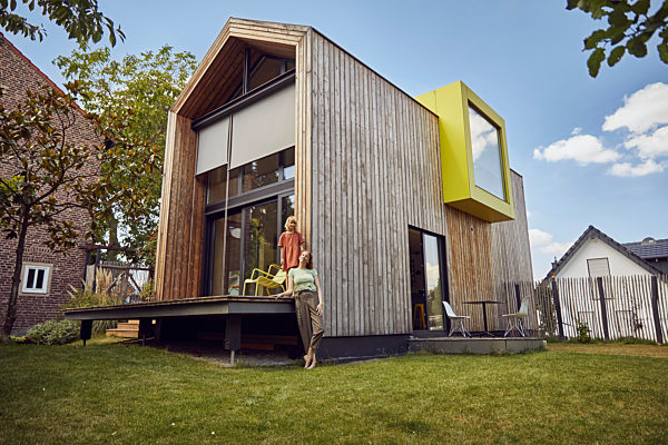 Mother and daughter standing outside tiny house in yard