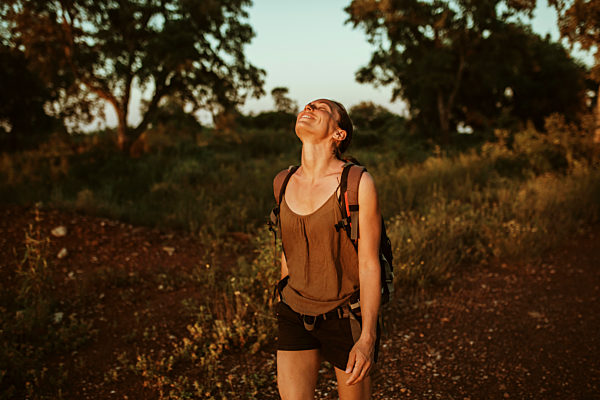 Smiling woman with head back hiking in forest