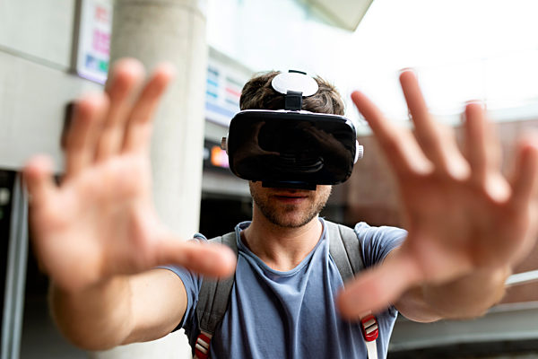 Young man gesturing while enjoying virtual reality headset at subway station