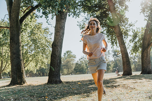 Mature woman jogging in public park on sunny day