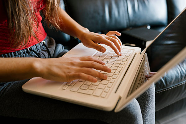 Teenage girl using laptop while sitting on sofa at home