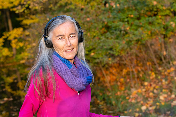 Mature woman listening music through headphones at park