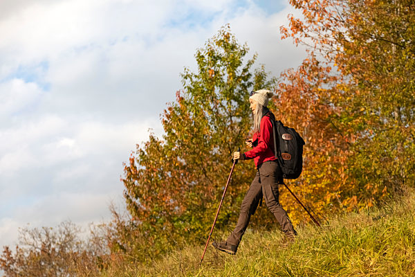 Female hiker with backpack and hiking pole walking on mountain at Alpine Foothills, Germany