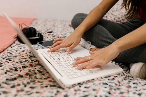 Teenage girl trying on laptop while sitting on bed