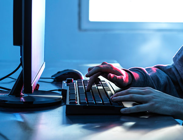 Hands of teenage boy breaching data from computer on desk