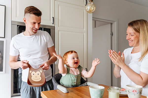 Happy family with baby daughter at kitchen table
