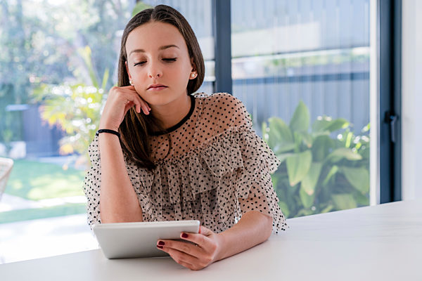 Teenage girl using digital tablet while sitting at table