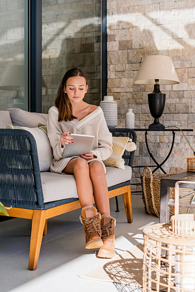 Teenage girl using digital tablet while sitting on sofa at home