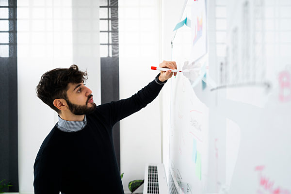 Businessman having presentation in office, writing at whiteboard