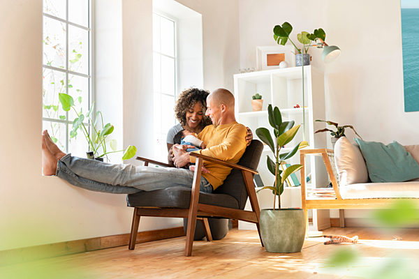 Smiling mother and father looking at their sleeping baby in living room