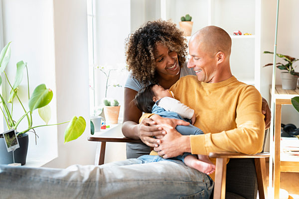Happy parents with sleeping baby in living room