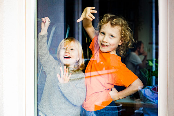 Playful siblings seen through glass door