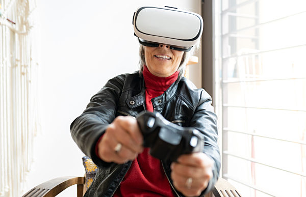 Smiling woman with controller playing games through wearable computer at home