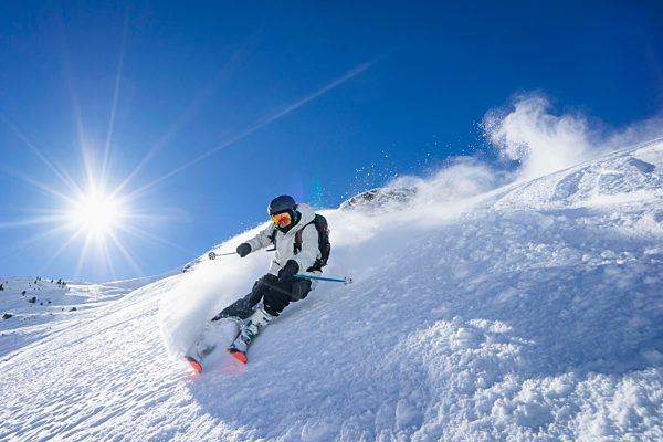 Sun shining over young man skiing in Arlberg massif