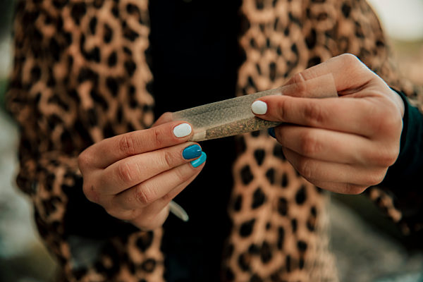 Woman rolling marijuana cigarette outdoors