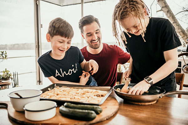 Happy boys preparing food with father in kitchen at houseboat