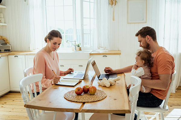 Male and female professionals working at dining table in kitchen