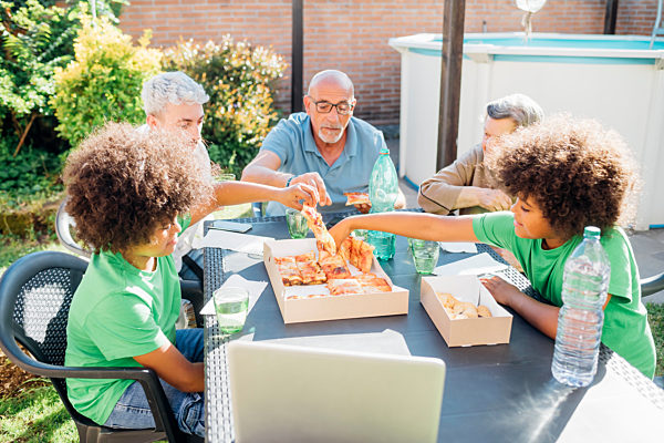 Multi-ethnic family enjoying snacks on table in back yard