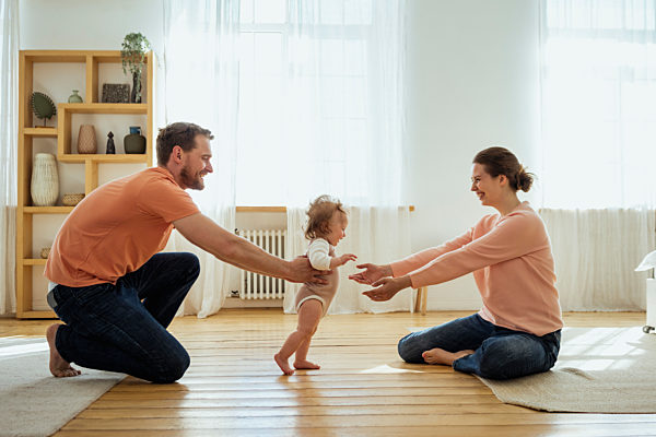 Parents helping daughter walking at home
