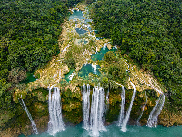 Aerial view of waterfall from rock formation amidst green trees, Huasteca Potosi, Mexico