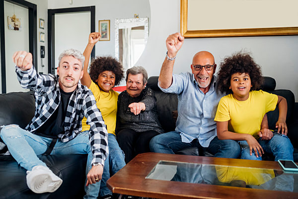 Cheerful multi-ethnic family celebrating victory at home