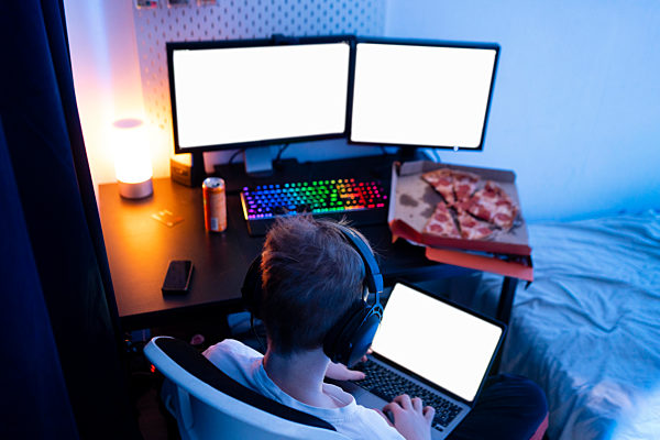 Gamer boy using laptop near table at home