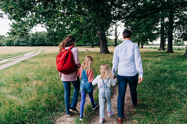 Daughters holding hands of parents while walking at park