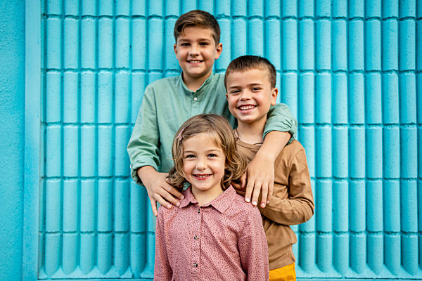 Smiling siblings standing in front of blue wall