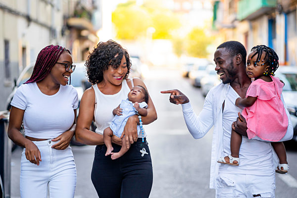 Happy man gesturing while walking on road with family