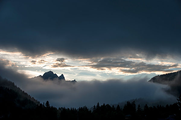 Gray clouds over thick fog in Ennstal Alps at dusk